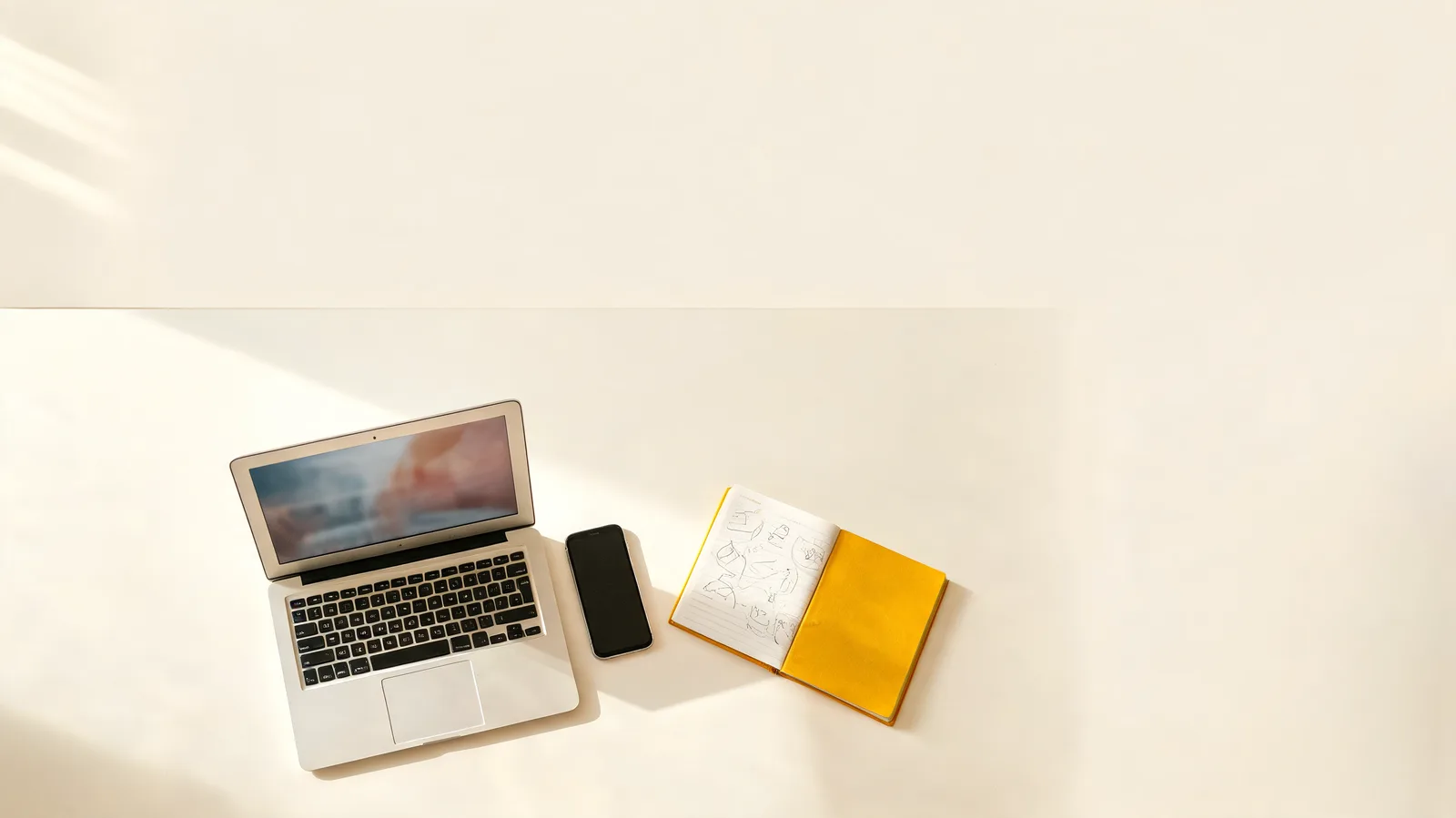 Mesa de trabalho criativo com notebook, celular e caderno de planejamento de marca